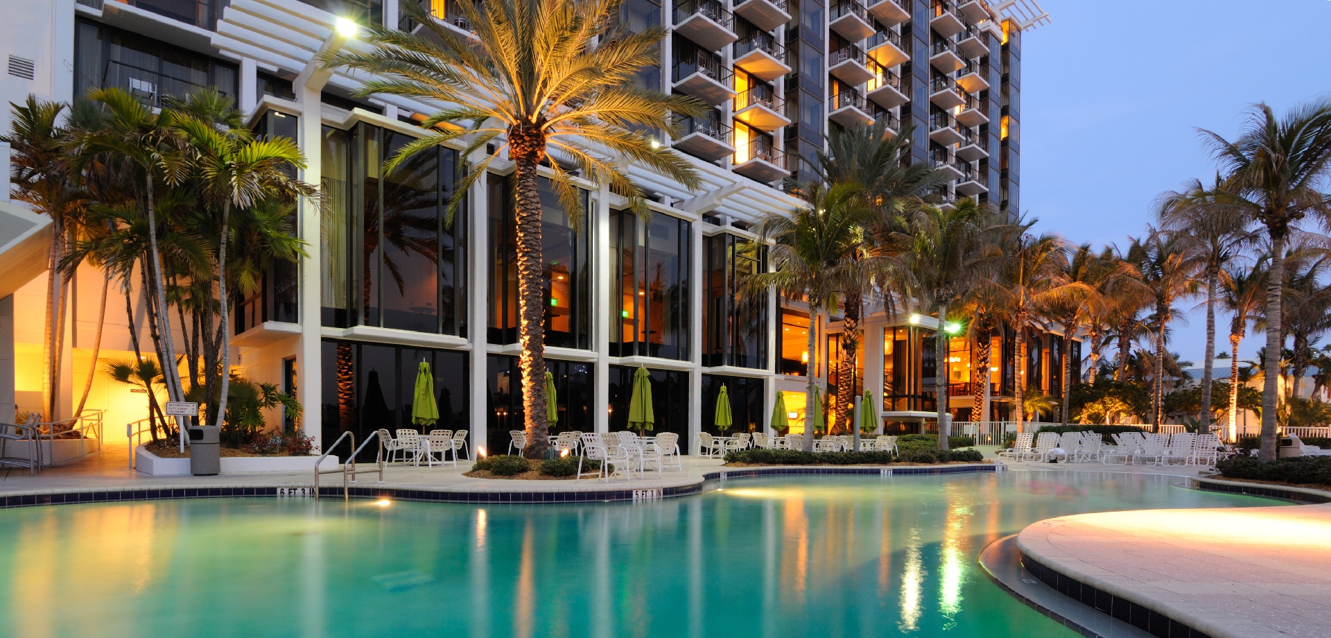 a poolside with hotel in the background