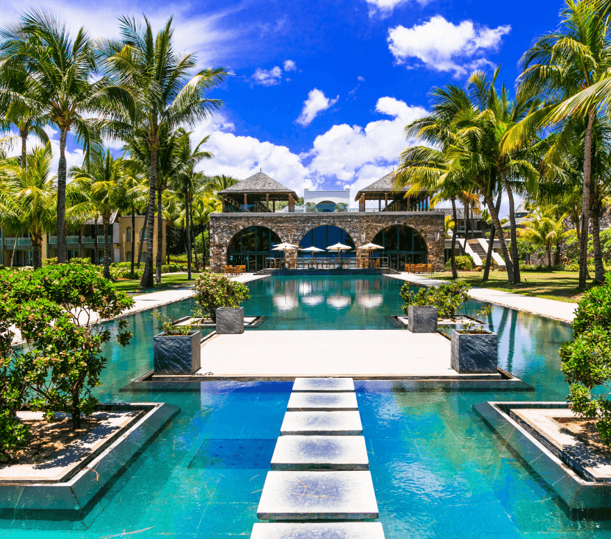 pool with walkway in the middle with resort in the background