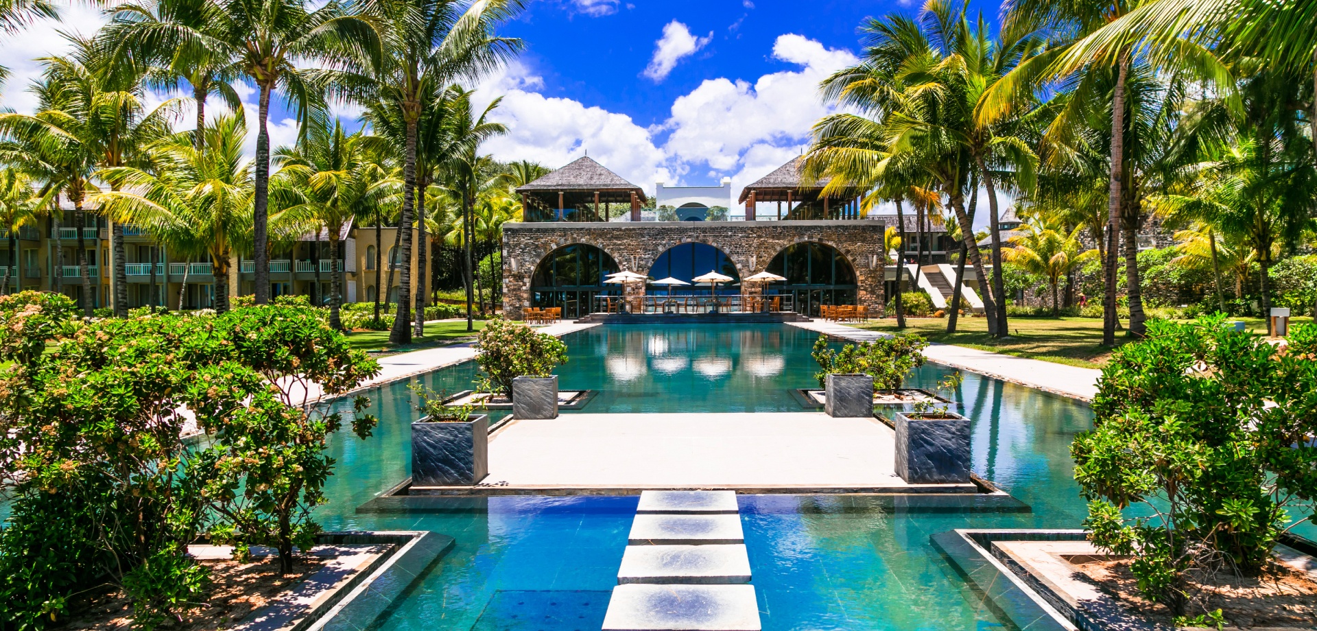 walkway in the middle of pool with resort in the background